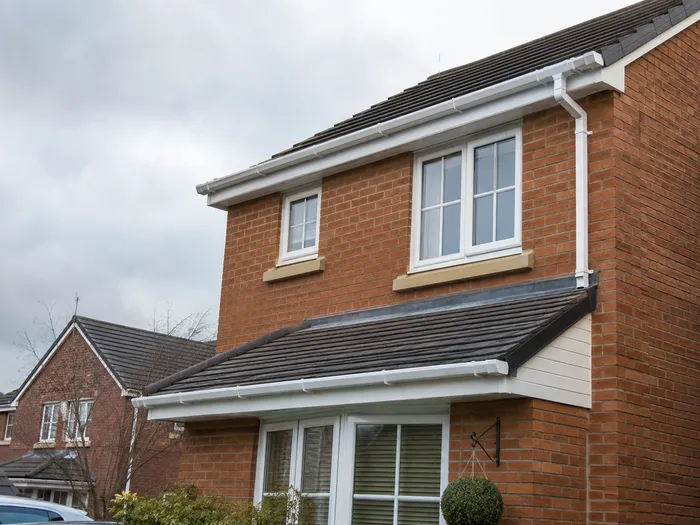 White guttering and downpipe fitted to a brick property